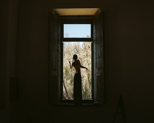 Persona realizando estiramientos suaves por la mañana junto a una ventana con luz natural